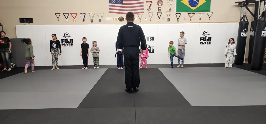 Coach facing a line of kids lined up on the mats at the start of class
